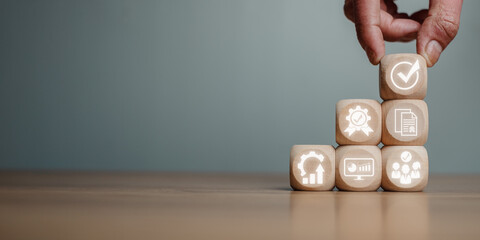 QA, Quality management assurance concept, Hand holding wooden block on desk with quality management assurance icon on virtual screen.