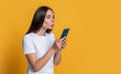 Connected online woman sending kisses to someone on video phone call using smartphone isolated on yellow, copy space
