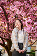 Woman allergic enjoying after treatment from seasonal allergy at spring. Portrait of happy beautiful woman smiling in front of blooming sakura tree at springtime. Spring allergy concept.