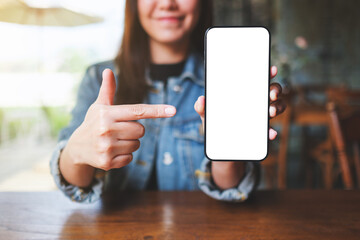 Wall Mural - mockup image of a woman holding, showing and pointing finger at a mobile phone with blank white scre