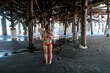 Teen girl standing under pier at the beach