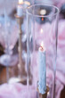 Close-up of a lit blue candle with dripping wax, set against ele