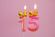 Pink birthday candle with bow and word happy burning on pink background., number 15.