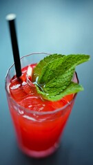 Sticker - A red drink with ice and mint in a transparent glass, on a blue background. Vertical