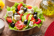 Greek salad on  wooden table served and ready to eat.