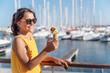 Happy, smiling girl holding ice cream cone with colorful ice cream balls. Sunny sea coastline at the background.