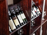 Fototapeta Lawenda - Bottles of wine displayed on the wine shelves in the restaurant or cafe close-up.