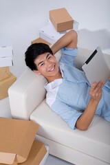 Shed on young man lying on the sofa playing tablet