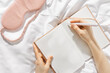 Woman takes notes or makes plan, day results on blank white page of paper in notebook or diary, holds notepad and pen in hands,  top view, time for yourself morning or evening before sleep