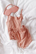 Pink female pajama and sleep eye mask on white cloth bed sheet. Top view comfort pyjamas for health sleeping. Romance mood, singlet and shorts for girl light pink trend color, sleepwear