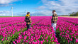 Two people standing gracefully in a vibrant field of purple tulips, surrounded by the beauty of nature in full bloom