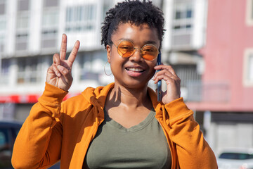 Wall Mural - afro woman making success or ok gesture with the phone on the street