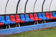 Bench of a football stadium with red and blue seats. No players