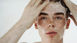 Close-up portrait of a young male with foamy soap on his face, emphasizing daily skincare routine.