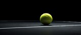 Fototapeta  - A tennis ball is lying on a black surface creating a simple and visually appealing image with space for text or other elements. Copy space image. Place for adding text and design