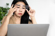 asian woman tired eye and taking of glasses,  suffering from eye strain, dry eyes after working on laptop screen