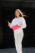 © MM - Business Woman in a white shirt and white pants Stands with a folder in her hands and checks documents