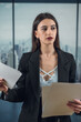 Single beautiful business woman in black suit holding paper doc standing in modern office