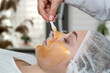 Woman enjoying soothing pampering golden facial mask by beautician at spa salon