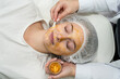  beautiful young woman lying with closed eyes and receive rejuvenation golden facial mask