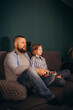 Photo of little funny lady amazed handsome dad sit cosy sofa good mood holding joystick playing video games excited rejoicing one team work house room indoors