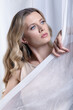 Portrait of a young woman against a background of white fabric. Female beauty concept.