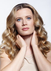 Wall Mural - Portrait of a young woman on white background. The woman with longa wavy hair is wearing a cream beige dress