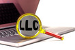 LLC word on magnifier on laptop , white background