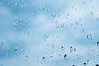 Rain drops on a window on blue sky background