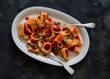 Paccheri pasta with tomato sauce and rosemary is a delicious vegetarian lunch on a dark background, top view