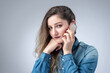 Portrait of a sweet sad young girl talking on a smartphone on a gray background