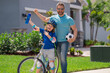 Kids insurance. Fathers day. Sporty family. Excited father and son with winning gesture. Father support child. Fathers love. Sporty kids. Cute boy with dad cycling in summer park outdoor.