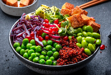 Wall Mural - Vegan Buddha Bowl for balanced diet with roasted tofu, red quinoa, vegetables, legumes, seeds and sprouts. Black table background, top view