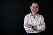 Portrait of smiling asian businesswoman ceo boss bank employee worker manager in formal wear white button up shirt standing with her arms crossed isolated on dark black background.
