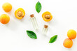 Apricot kernel oil among apricots and leaves on white background top view pattern