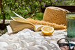 Reading during summer holidays. Book, rifresh drink, sunglasses and hat on white beach blanket on wicker chair in tropical garden. Summertime mood.