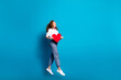 Photo of pretty young woman hold red heart postcard run look empty space dressed stylish white clothes isolated on blue color background