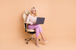 Full body photo of nice retired female sit office armchair hold netbook wear trendy formalwear isolated on beige color background