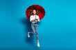 Photo portrait of nice young lady excited jump hold umbrella wear trendy white garment isolated on blue color background