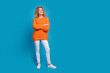 Full length photo of adorable pretty woman wear stylish orange clothes crossed arms look empty space isolated on blue color background
