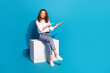 Photo portrait of nice young lady sit cube point empty space wear trendy white garment isolated on blue color background