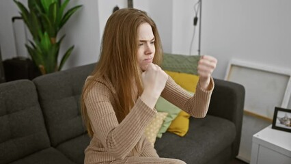 Sticker - Furious blonde woman in sweater at home, young, aggressive, frustrated and mad, raising fists in anger