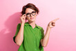 Photo of charming cute young woman dressed green shirt hand eyewear showing finger empty space isolated pink color background