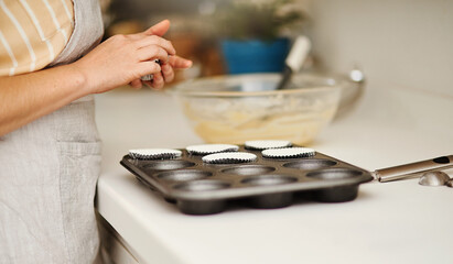 Wall Mural - Baker hands, baking tray and cupcakes prepare in kitchen in house for relax or therapeutic hobby. Dessert, cooking and professional person with homemade for small business or home recipe with paper.