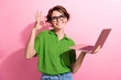 © deagreez - Photo portrait of pretty young girl hold netbook show okey symbol wear trendy green outfit isolated on pink color background
