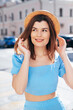 Young beautiful smiling hipster woman in trendy summer blue clothes. Sexy carefree woman posing on the street background at sunset. Positive model outdoors. Cheerful and happy and hat