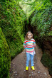 Happy little preschool girl hiking through a cave. Child having fun with activity.