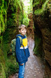 Teenager boy with backpack hiking through a cave. Happy school child having fun with activity.