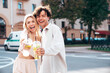 Young smiling beautiful woman and her handsome boyfriend in casual summer clothes. Happy cheerful family. Female having fun. Couple posing in street. Holding and drinking cocktail drink in plastic cup
