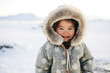 Joyful Inuit child with fur hood smiling in snowy environment